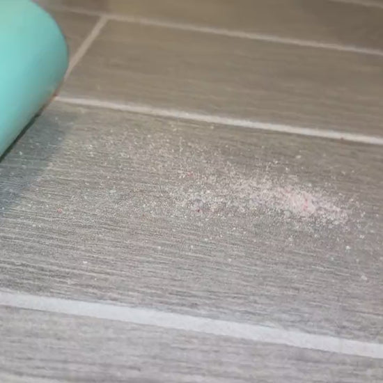 The large hand roller in action cleaning sand off a tile floor