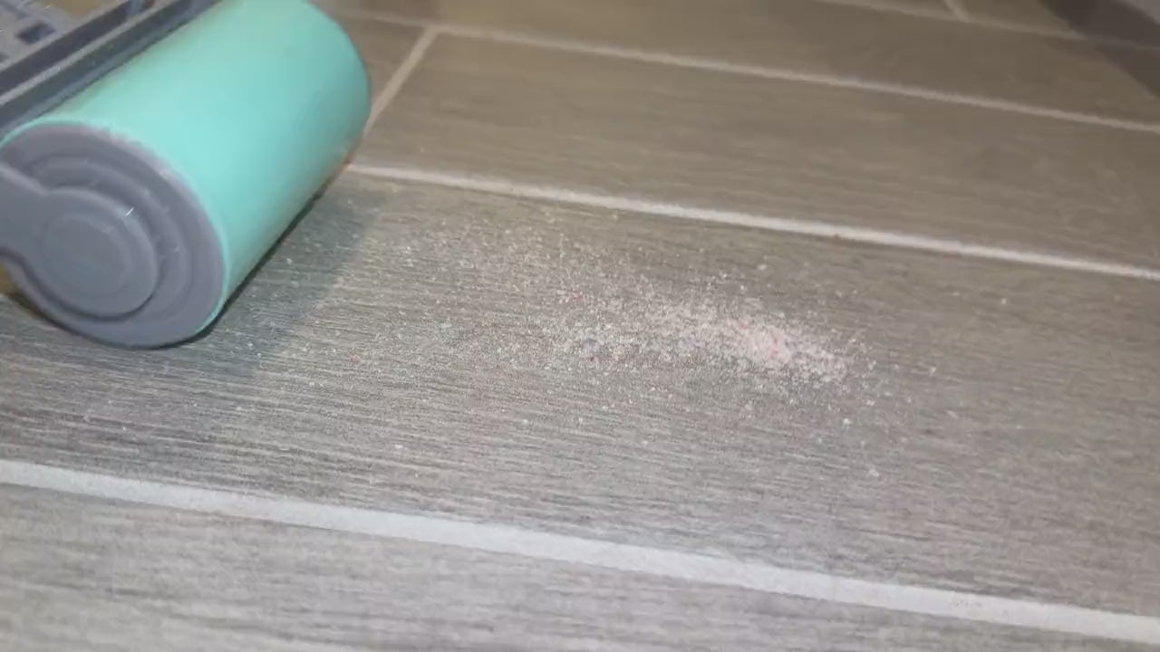The large hand roller in action cleaning sand off a tile floor